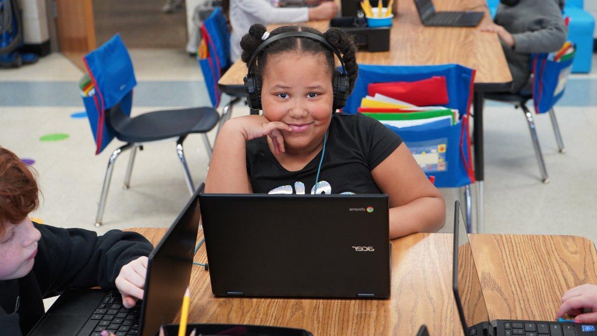 girl smiling behind laptop screen